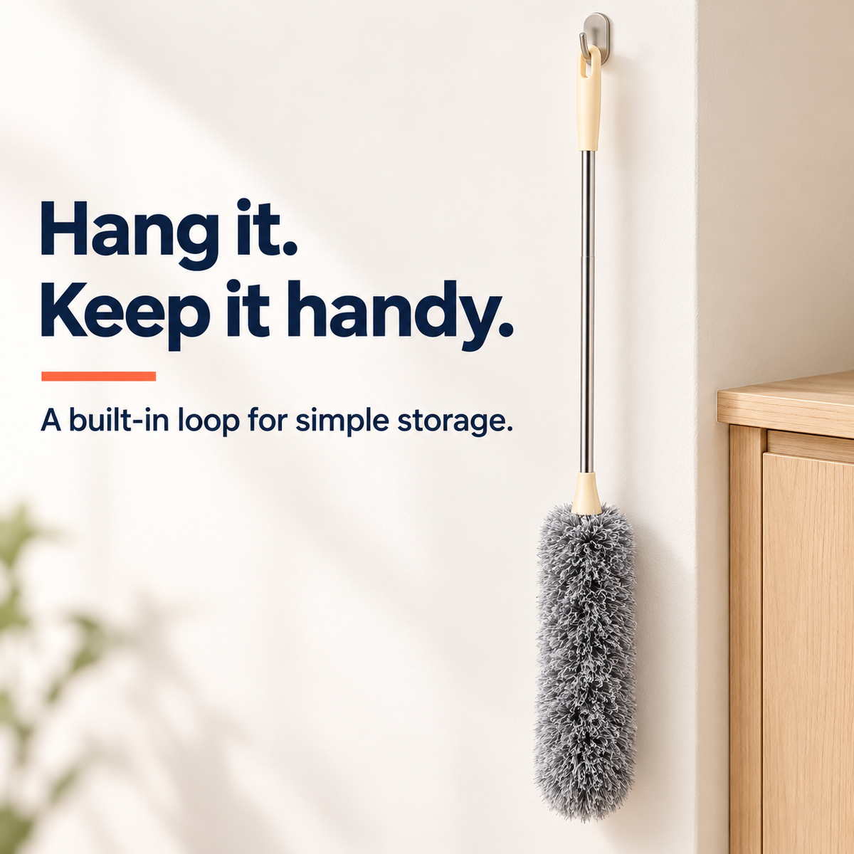 Duster hanging from its cream handle loop on a wall hook beside a cupboard